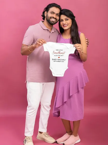 A personalized baby onesie makes for a perfect announcement prop. This couple holds up a custom outfit for their "little sweetheart."