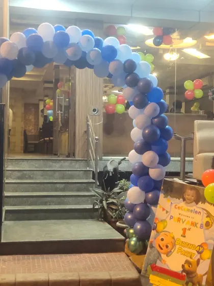 A blue and white balloon arch and welcome sign for a Cocomelon-themed first birthday party.