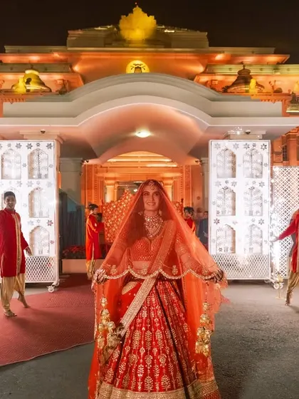 A classic bridal entry that is always breathtaking. The bride, in a stunning red lehenga, is revealed to the guests, flanked by dancers in coordinated outfits, creating a regal and timeless picture.