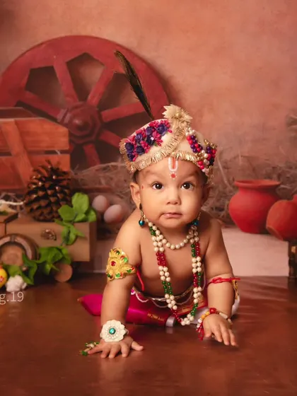 A close-up of a crawling baby Kanha, looking directly at the camera with the sweetest expression.