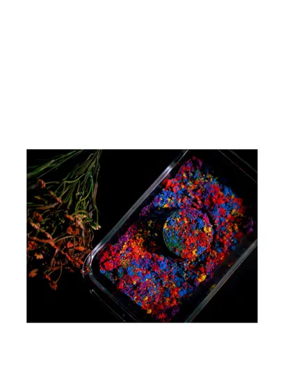 The edited version of the Holi color product shot. The deep blacks and saturated colors make the product pop, showcasing a more artistic approach to product photography.