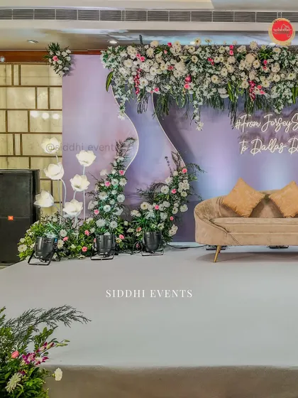 A side angle of the lavender-themed engagement stage, highlighting the asymmetrical floral design and the soft glow of the custom neon hashtag.