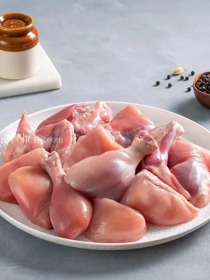A plate of assorted raw chicken cuts, including drumsticks and thighs, shot on a clean, light-grey background for Zappfresh.