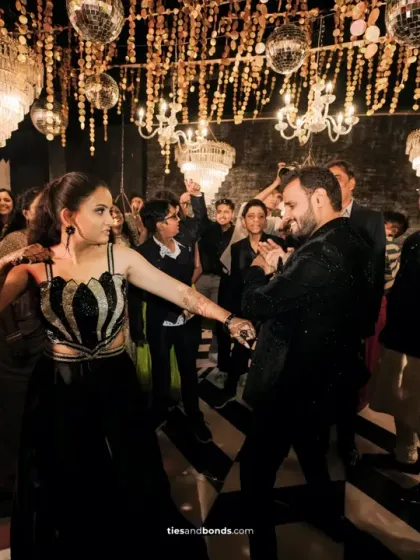 Guests dancing the night away on the black and white checkered floor, under a ceiling of disco balls and chandeliers.