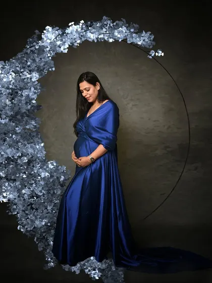 This portrait uses a crescent of blue flowers to create a dreamy, celestial theme, celebrating the magical journey of motherhood.