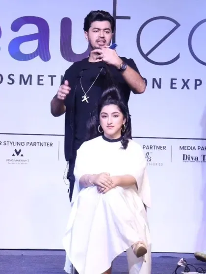 On stage at the Beautech Expo, demonstrating a haircutting technique to a large audience.
