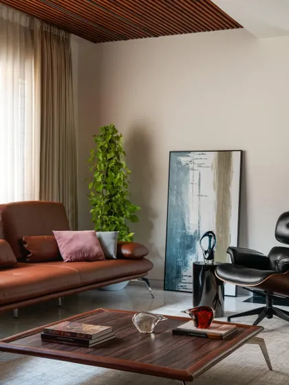 A detail of the informal living room at Timber Edge, showcasing the combination of a leather sofa, abstract art, and a slatted wood ceiling.
