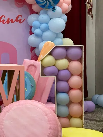 A balloon-filled number "1" prop as part of a candyland first birthday, surrounded by giant candy and ice cream decorations.