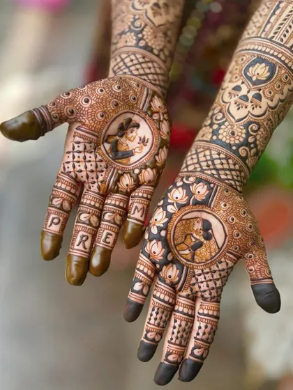 A close-up of the portrait work. You can see the bride holding a mirror on one palm and the groom on the other, surrounded by delicate lotus and jaali patterns.