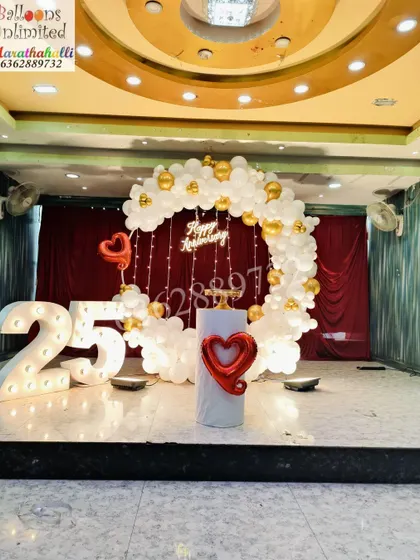 A stunning Silver Jubilee celebration for a 25th anniversary, with a white and gold balloon ring, fairy lights, and a large illuminated number '25'.