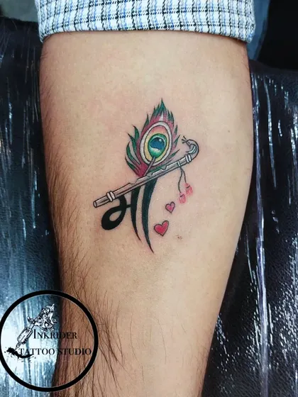 A creative design combining the word 'Maa' (Mother) with a peacock feather and a flute, symbolizing a mother's divine and beautiful nature.