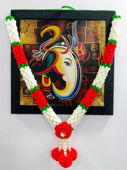 This Mogra Haar, inspired by delicate jasmine buds, is perfect for daily pooja. The classic red and white design brings a touch of traditional elegance to this photo of Ganpati Bappa, and it's completely washable and reusable.
