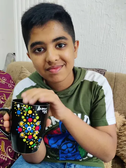 Another happy guest showing his completed dot art mug, a unique party favor he made himself.
