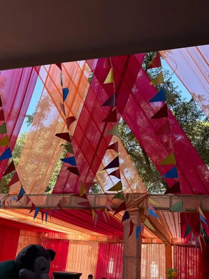 Colorful fabric draping on the ceiling for an outdoor event. This adds a festive and vibrant touch to the overall decor.