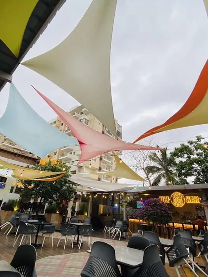 The outdoor area of 'The Big Barn' pub, where we designed and executed the complete landscape. The space features colorful tensile shades, comfortable seating, and a variety of plants, including a statement Bougainvillea, to create a relaxed, festive vibe.