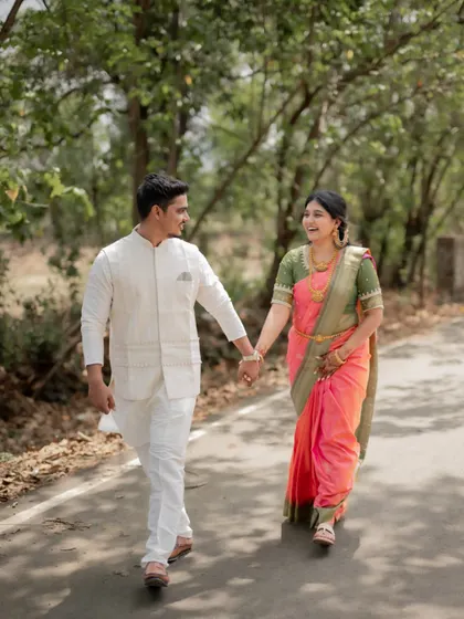 A candid shot of a couple walking down a country road for their engagement shoot, dressed in beautiful traditional attire.