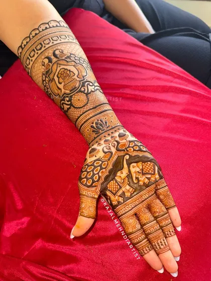 A side view of the bridal henna, highlighting the detailed elephant figures on the palm and the floral bands on the arm.