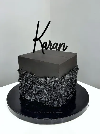 Black is hot. A minimalist and modern black cube cake with a rugged, textured base, perfect for a sophisticated celebration.