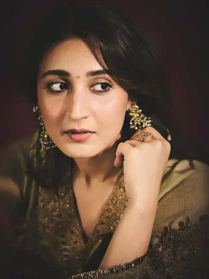 A warm, intimate portrait of Dhvani. This shot captures her soft expression and highlights the beautiful gold embroidery and traditional jhumka earrings.