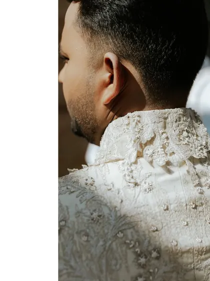 A view of the detailed embroidery on the back and collar of the groom's custom Shantanu & Nikhil wedding sherwani, showcasing exquisite craftsmanship.