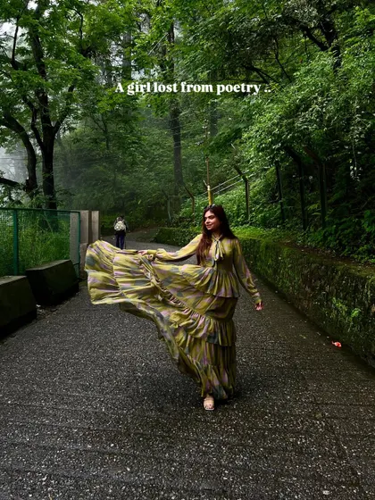 A girl lost in poetry. The flowing dress against the green, misty backdrop creates a dreamy and romantic image.