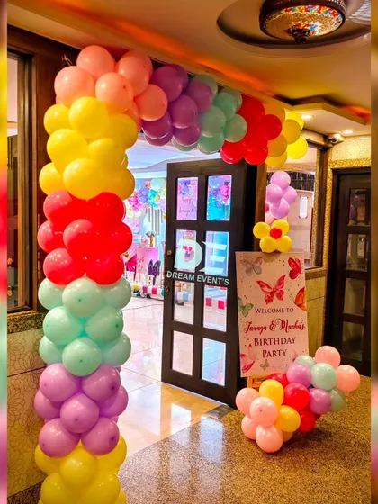 A vibrant rainbow balloon arch marks the entrance to the twins' butterfly-themed birthday party. It creates a fun and exciting welcome for all the guests.