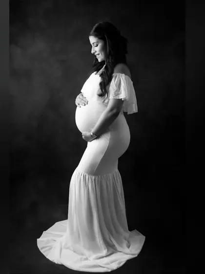 This is another example of a classic black and white portrait. The soft lighting and the simple white gown create a gentle, elegant look, highlighting the pure joy of this mom-to-be.