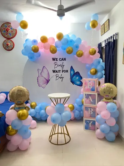 A classic gender reveal setup with a "We Can Bearly Wait for Baby" butterfly theme, using pink and blue balloons.