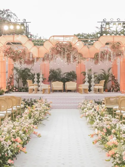 The full view of the 'Gulab Bagh' wedding aisle and mandap. The path is lined with lush flowers, leading to the glowing organza structure for a dramatic and romantic effect.
