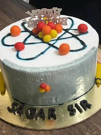 A cake for the science enthusiast! This design features an atom model on top, with molecules and other science-themed details, personalized for "Sagar Sir".
