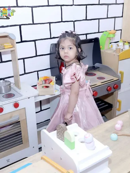A little guest takes a break from the party to cook up some fun in our pretend play kitchen.