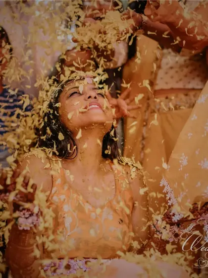 The bride looking up blissfully as flower petals rain down on her.