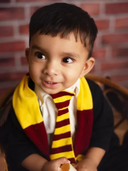 A close up of our little wizard, looking curious and magical. The Gryffindor scarf and tie are perfect details for any Harry Potter fan.