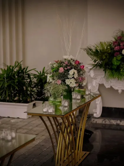 Elegant console tables with gold accents and classic white furniture are used to display floral arrangements and create decorative vignettes throughout the event space.