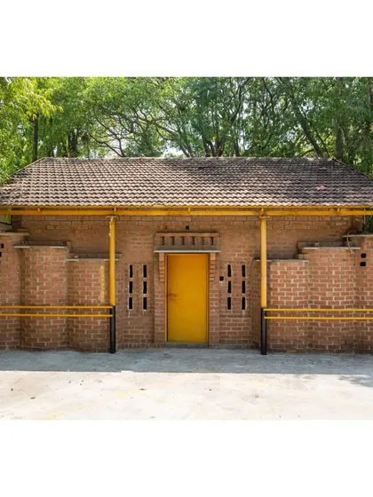 The rear facade of the Spastic Society classroom, featuring stepped brick buttresses and small window openings. The design is both structurally sound and visually interesting.