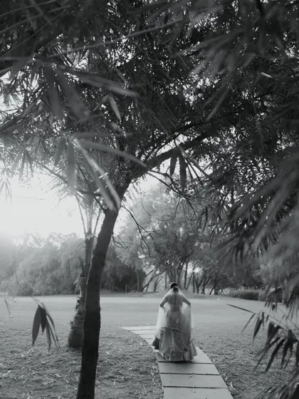A black and white shot of the bride walking away, framed by bamboo trees. This artistic photo has a quiet, contemplative feel.