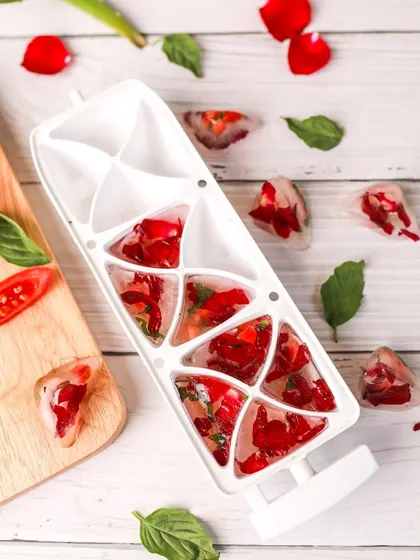 A creative shot of DIY skincare ice cubes filled with rose petals and basil. This image is fresh, vibrant, and perfectly communicates the natural ingredients used.
