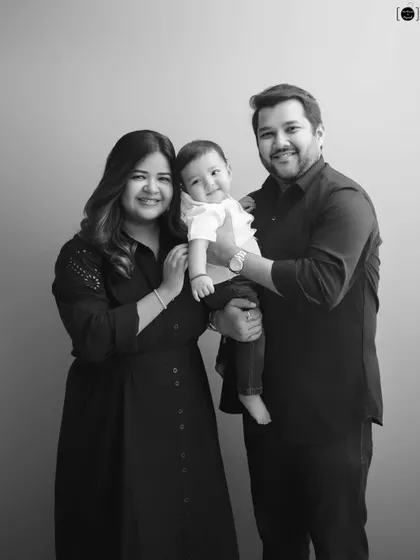 A classic black and white family portrait. By removing color, we focus on the light, expressions, and the happy connection between the parents and their baby.
