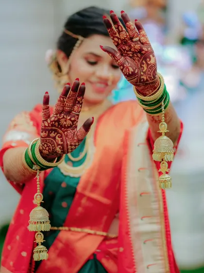 A playful shot of the bride showing off her intricate mehndi and traditional kalire, capturing her joyful spirit.