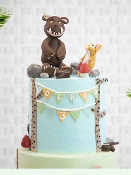 The top tier of the jungle cake, showcasing the hand-molded Gruffalo character and a personalized birthday banner.