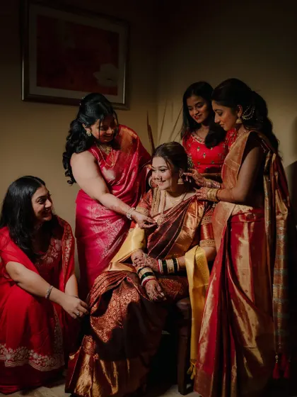A heartwarming candid shot of the bride surrounded by her bridesmaids and family, sharing a moment of joy and support as they help her get ready.