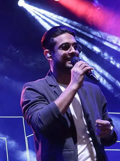 A portrait of Sanam Puri performing, with dramatic stage lighting and smoke effects managed by our production team.