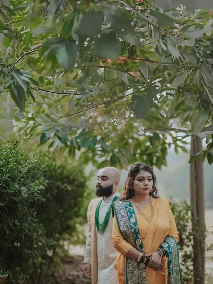 A beautiful portrait of the couple framed by nature. The groom stands behind the bride, both looking in the same direction, creating a sense of shared journey and destiny.