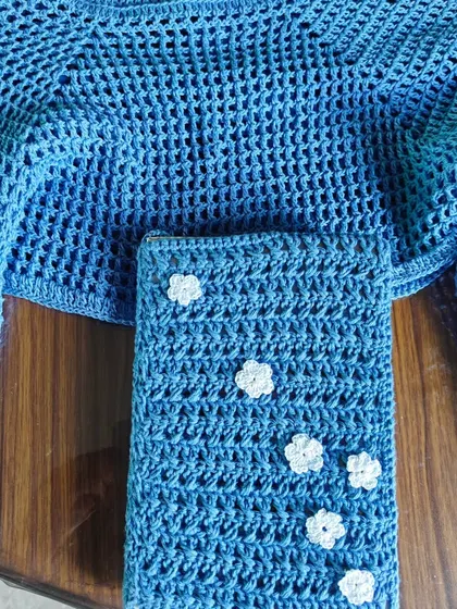I love creating matching sets! Here is a breezy, blue crochet crop top paired with a custom book cover, both detailed with delicate white daisy flowers. It’s a perfect example of how I blend fashion with functional art.