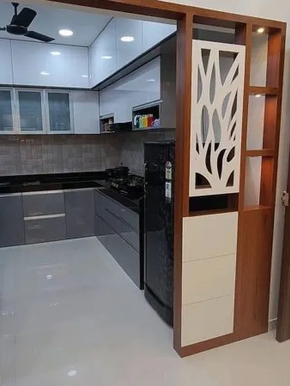 This kitchen is separated from the living area by a stylish wooden partition with CNC-cut jali work. This creates a semi-open layout that defines the space while allowing light to pass through.