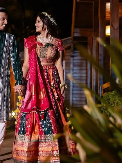 A vibrant night-time shot of a couple walking hand-in-hand, their colorful, sequined outfits shining under the lights.