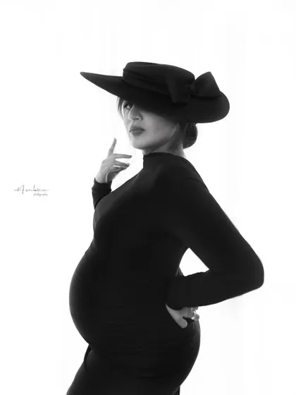 A powerful and confident pose in black and white. The angle and the dramatic hat create a high-fashion look, proving that maternity portraits can be both artistic and empowering.