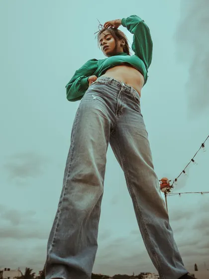 This variation on the low-angle shot gives a full view of the wide-leg jeans, showcasing their fit and style against a cloudy sky.