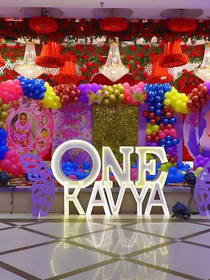 A full view of Kavya's spectacular butterfly-themed stage. The mix of bright primary colors with butterfly cutouts and light-up letters makes it a truly joyful setup.