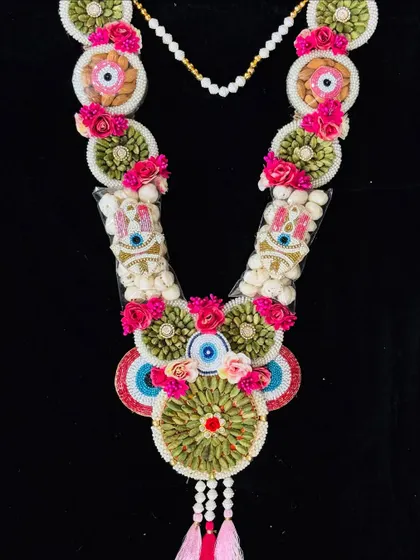 This dry fruit garland features a vibrant pink and green color scheme with evil eye details. It's a beautiful and healthy gift, perfect for adding a touch of tradition to your Holi celebrations.
